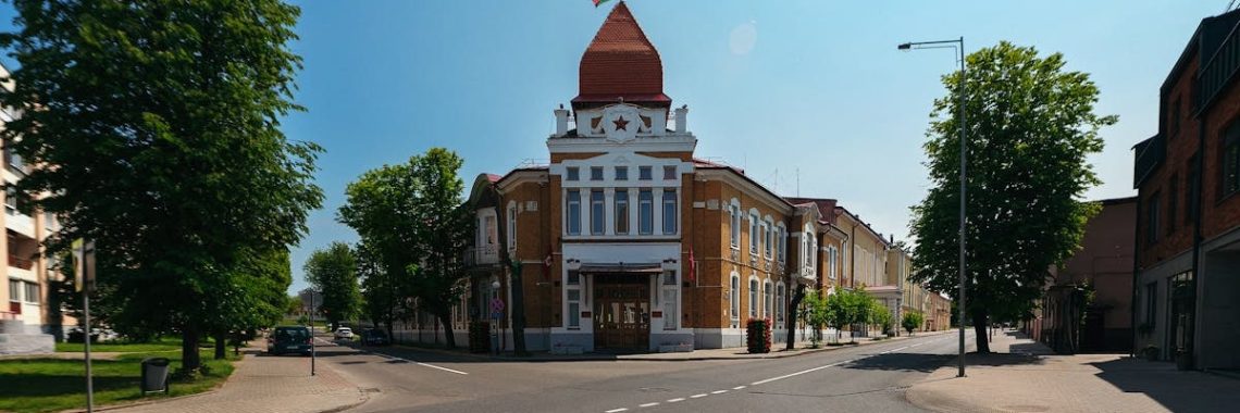 An empty street featuring a historic building with a red flag under a clear sky.