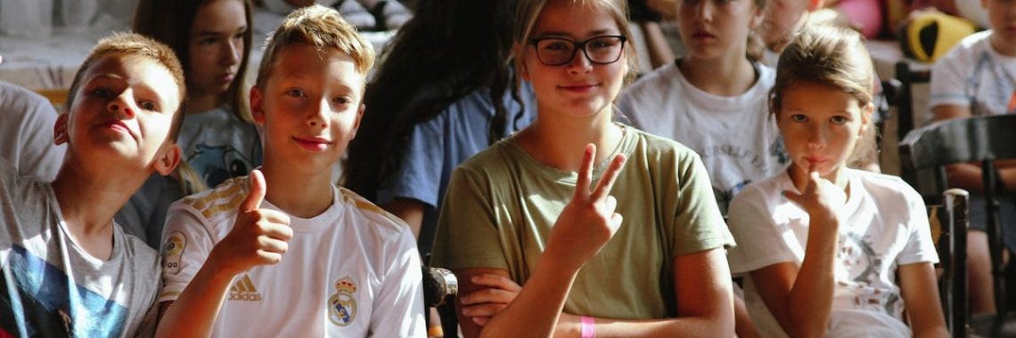 Cheerful group of children sitting together at an indoor event, showcasing friendships and diversity.