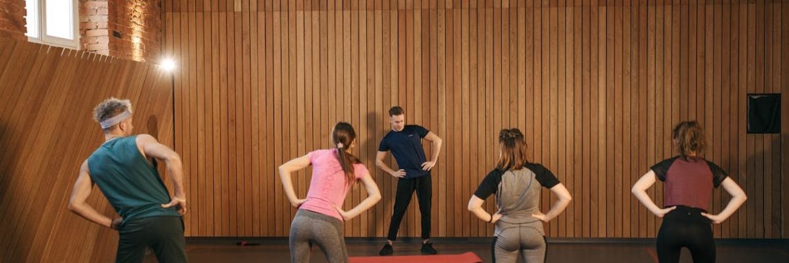 People stretching on yoga mats during a fitness class indoors.
